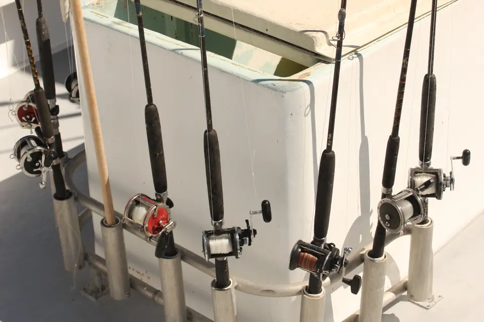 Several fishing rods with conventional reels secured upright in rod holders on a boat.