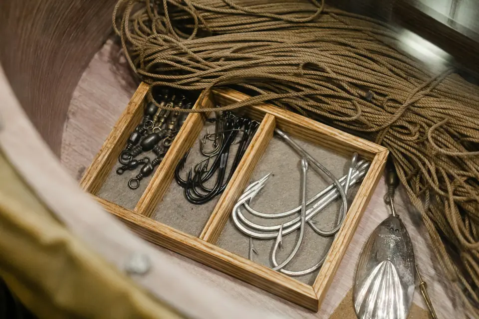 Smaller black hooks and larger silver hooks in separate compartments of a wooden tray.