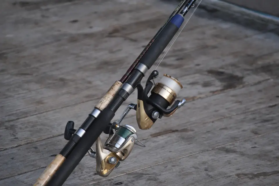Two spinning reels mounted on rods and resting on a wooden fishing pier.